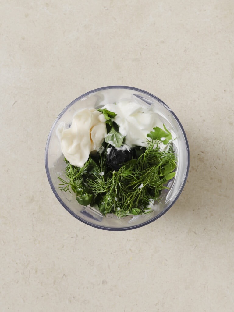 A small blender with fresh herbs and greek yogurt.