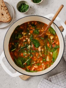Ikarian longevity stew with white beans, potatoes and spinach in a white Dutch oven