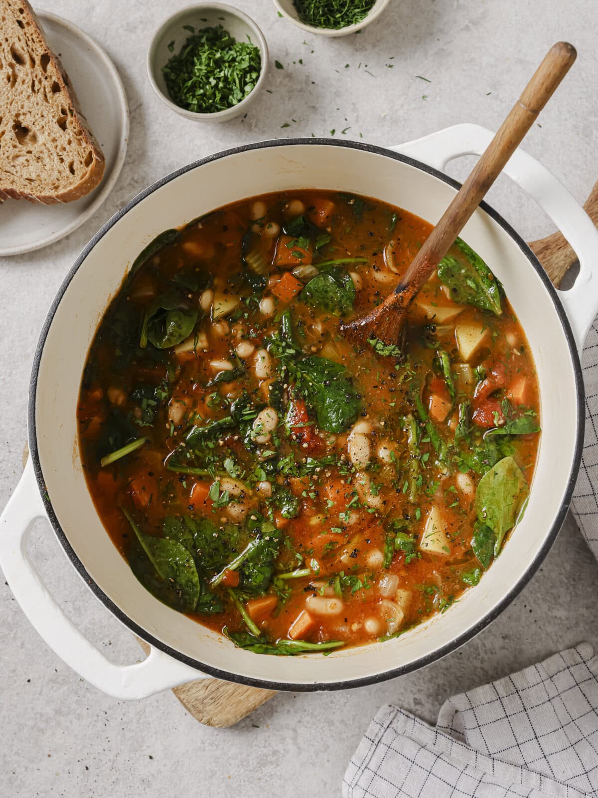 Ikarian longevity stew with white beans, potatoes and spinach in a white Dutch oven