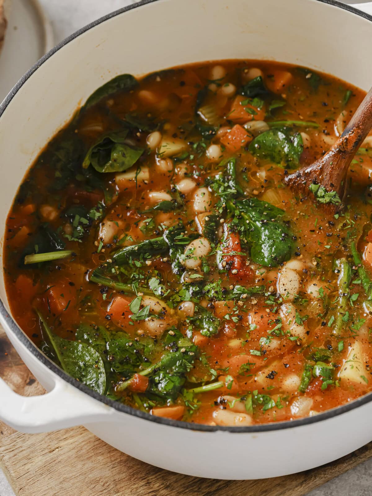 Ingredients for Ikarian longevity stew: white beans, diced vegetables, potato, tomatoes, spinach, herbs, garlic and broth