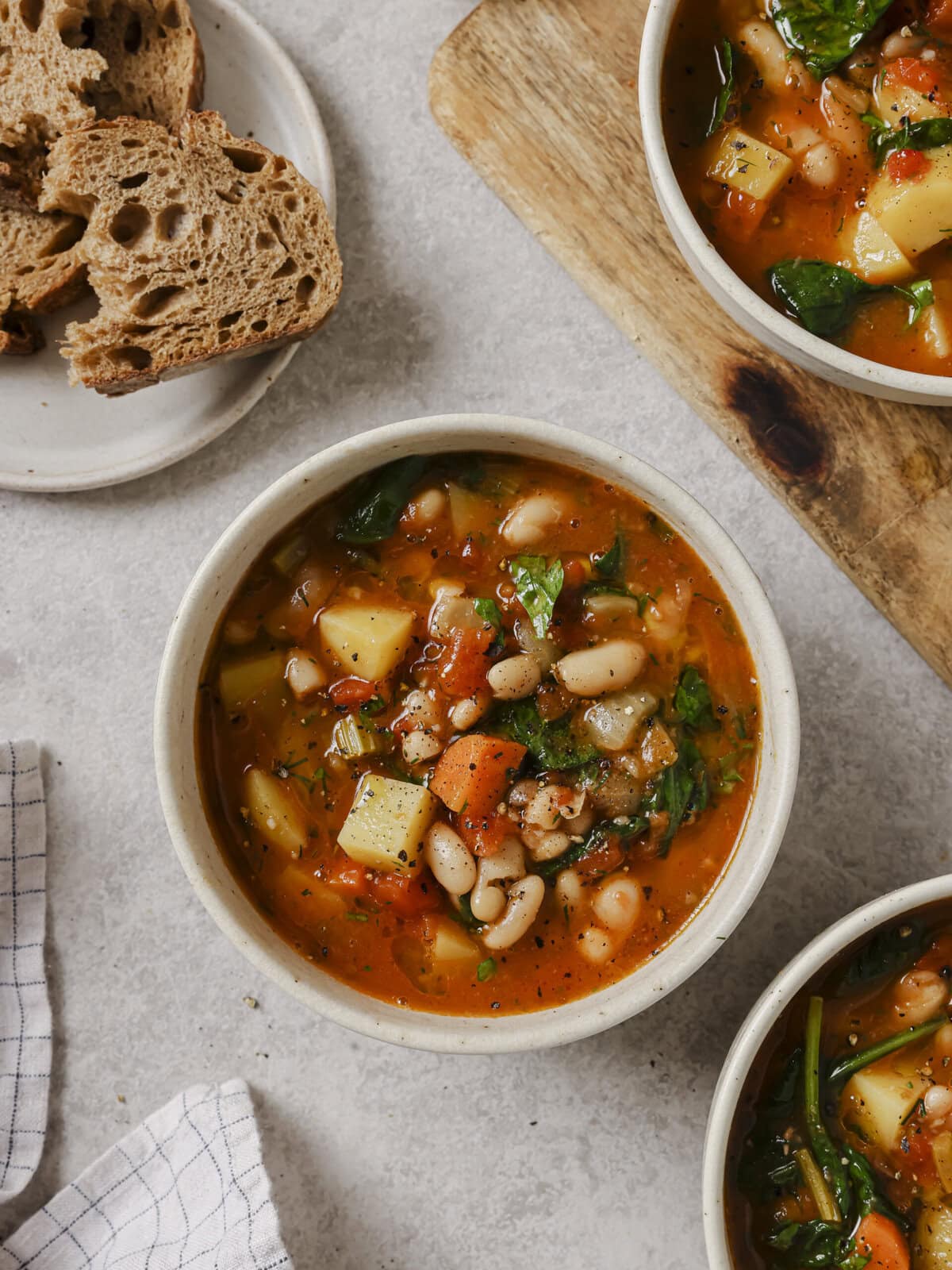 Bowl of Ikarian white bean and potato stew next to crusty bread
