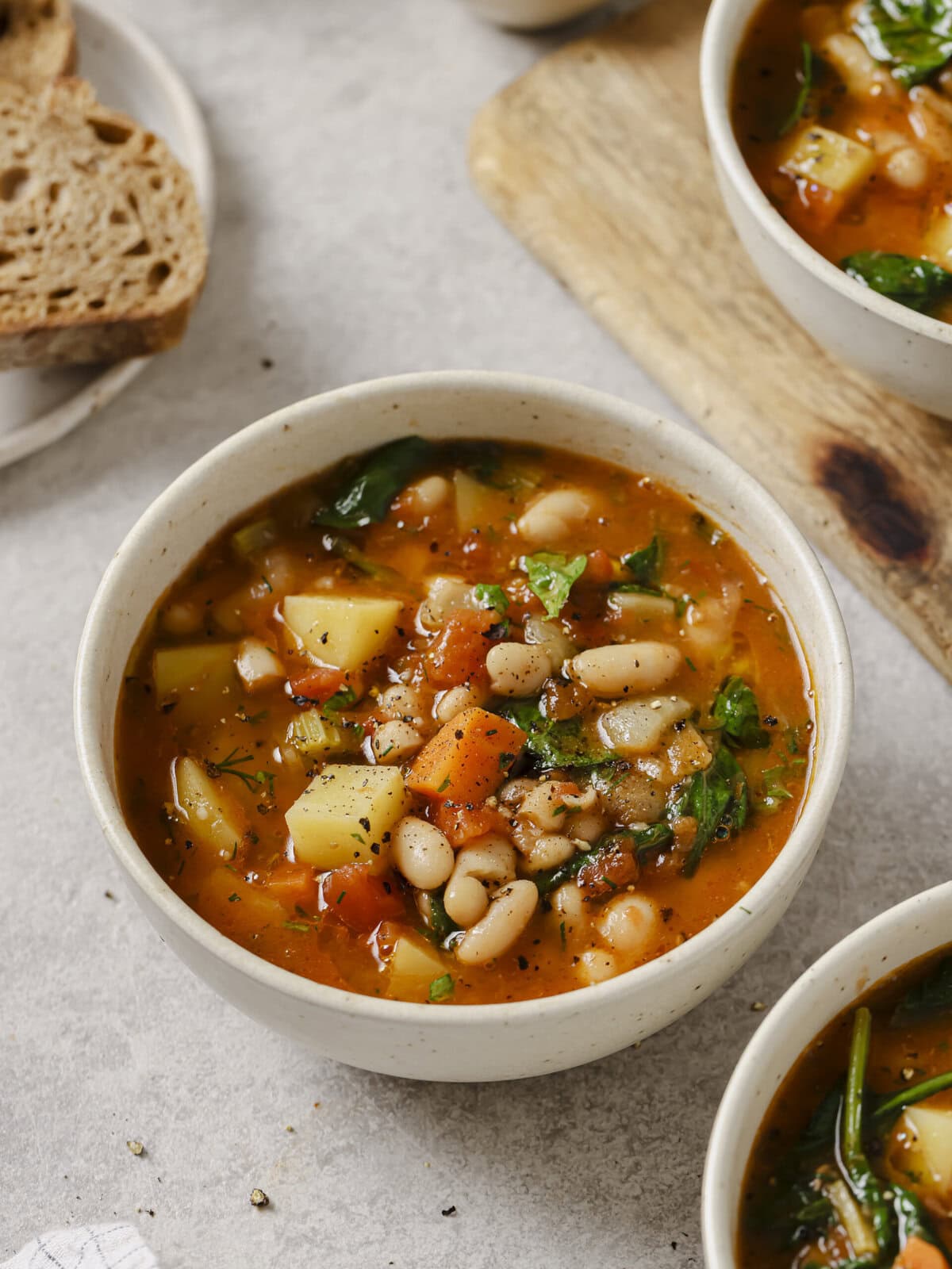 Ladle lifting white beans, potato and carrot from a pot of Blue Zones stew