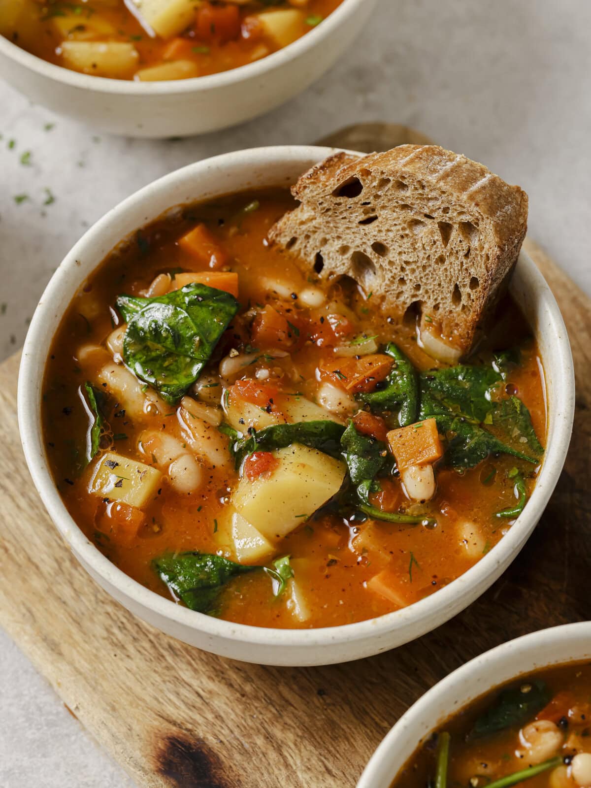 Bowl of Ikarian white bean stew with potato, carrot and fresh herbs